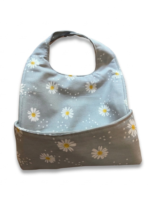 The Grey Daisies Nana Bib buttoned into its food-catching pocket on a white background